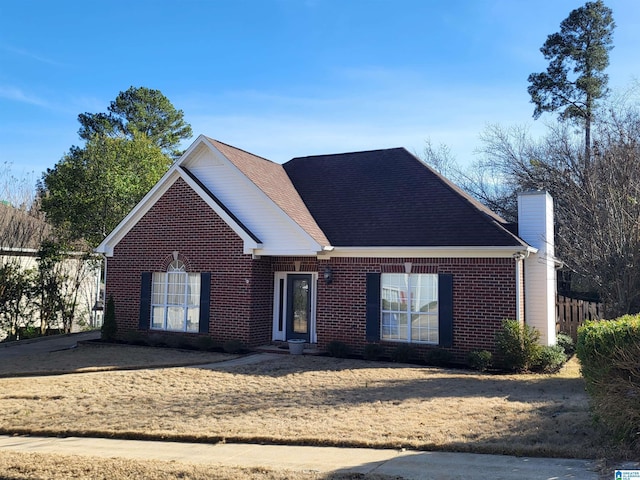 view of front of home featuring brick siding, a chimney, and roof with shingles