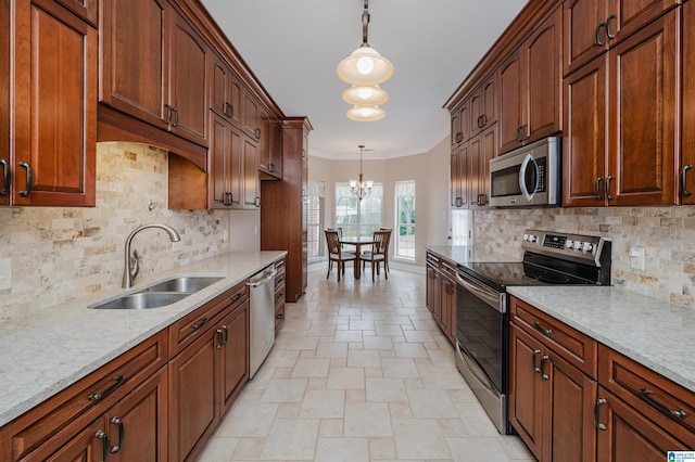 kitchen featuring pendant lighting, appliances with stainless steel finishes, ornamental molding, a sink, and light stone countertops