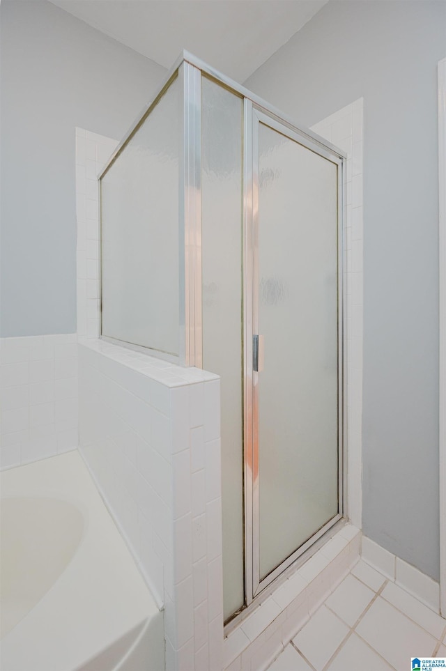 bathroom with a stall shower, a bath, and tile patterned floors