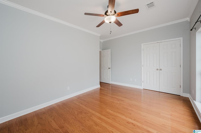 unfurnished bedroom with crown molding, light wood finished floors, a closet, visible vents, and baseboards