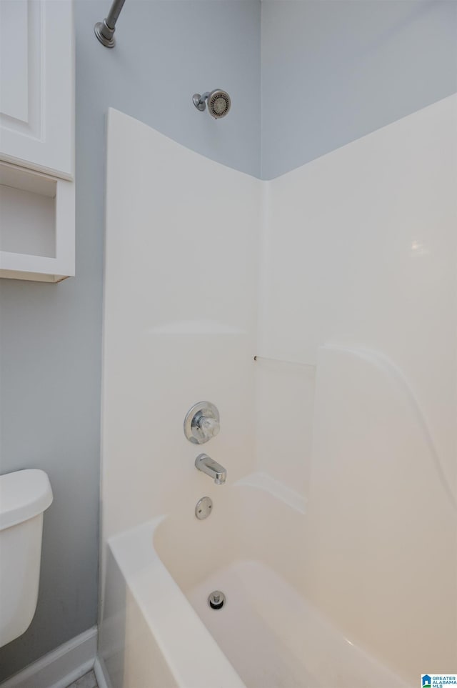 bathroom featuring shower / washtub combination, baseboards, and toilet