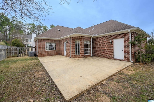 rear view of house with brick siding, fence, and a patio