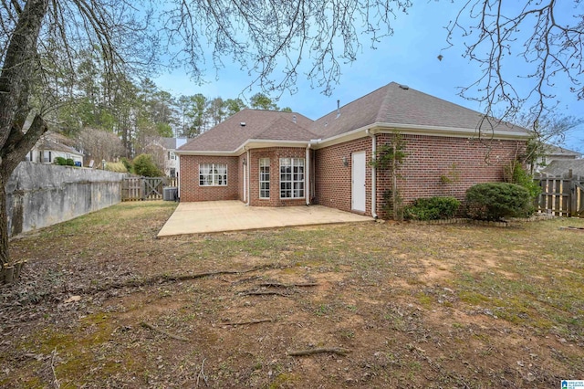 rear view of property with a patio, a fenced backyard, a garage, brick siding, and a shingled roof