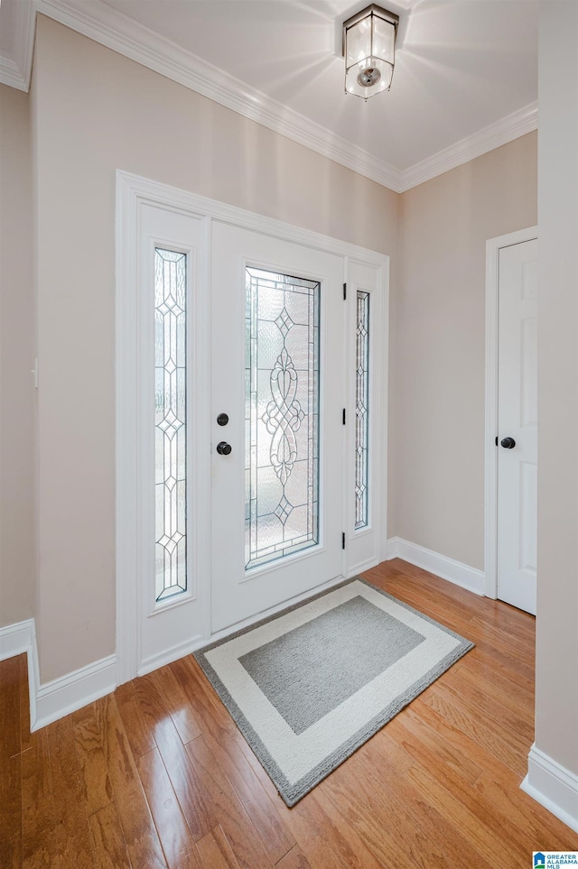 foyer entrance featuring baseboards, wood finished floors, a wealth of natural light, and crown molding