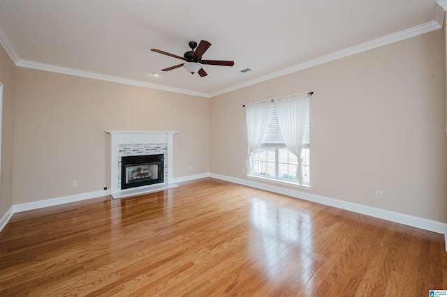 unfurnished living room with baseboards, ornamental molding, a tile fireplace, and light wood-style floors