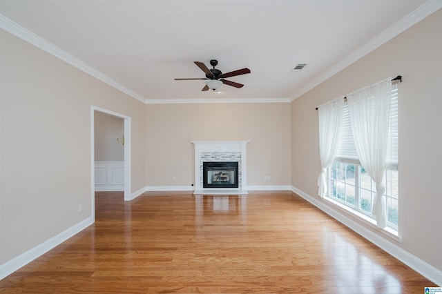 unfurnished living room with light wood-style flooring, a glass covered fireplace, visible vents, and crown molding