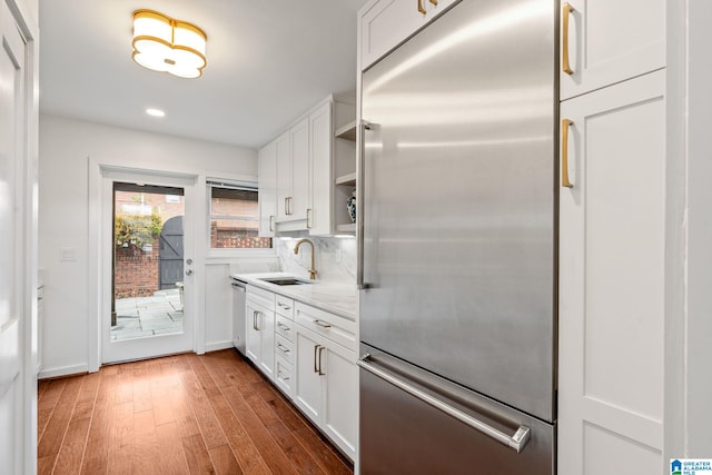 kitchen featuring open shelves, appliances with stainless steel finishes, white cabinets, a sink, and light stone countertops