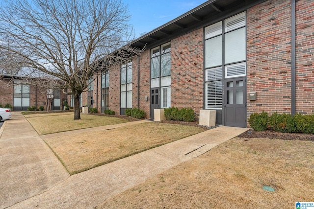 exterior space with brick siding and a lawn