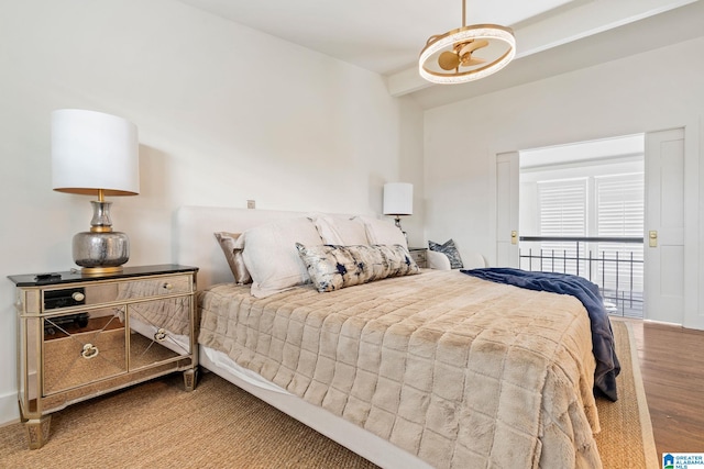 bedroom with beam ceiling and wood finished floors