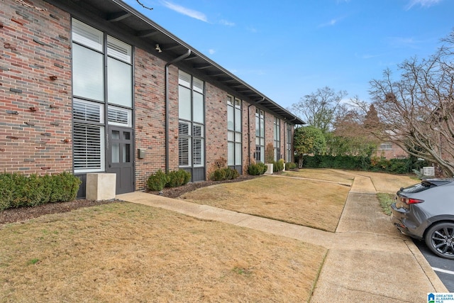 view of side of property with brick siding and a lawn