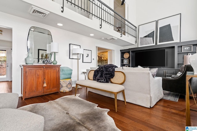 living area featuring dark wood-style floors, recessed lighting, visible vents, and a high ceiling