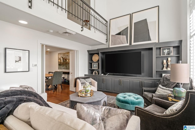 living area featuring a high ceiling, visible vents, wood finished floors, and recessed lighting