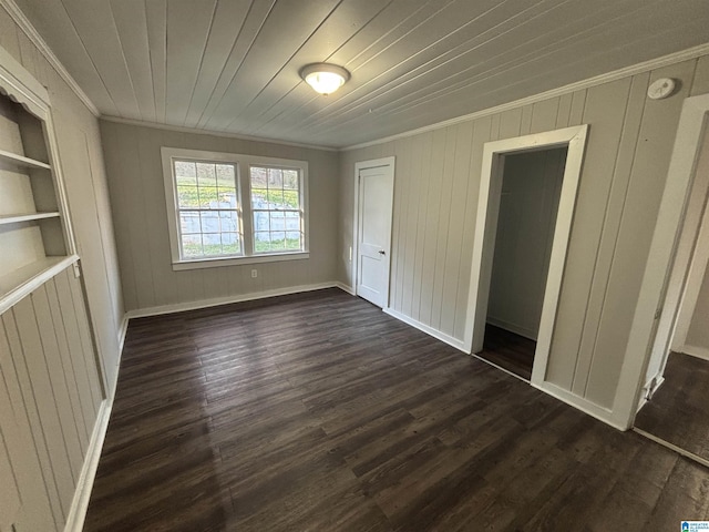 unfurnished bedroom with wooden ceiling, baseboards, a closet, dark wood finished floors, and crown molding