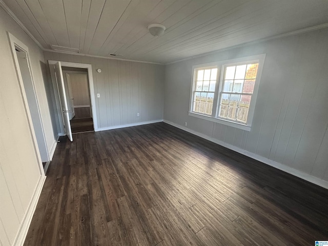 spare room featuring ornamental molding, dark wood-type flooring, wooden ceiling, and baseboards