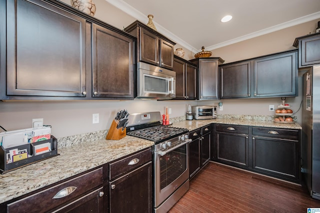 kitchen with dark wood finished floors, appliances with stainless steel finishes, ornamental molding, dark brown cabinetry, and light stone countertops