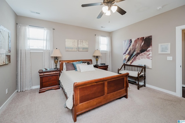 bedroom with light carpet, ceiling fan, visible vents, and baseboards