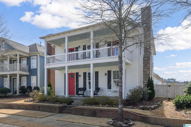 view of front of house featuring covered porch, fence, and a chimney