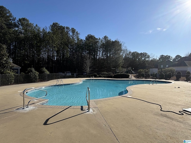 community pool with a patio area and fence