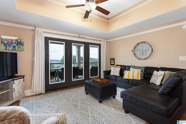 living room featuring ornamental molding, a tray ceiling, and a ceiling fan