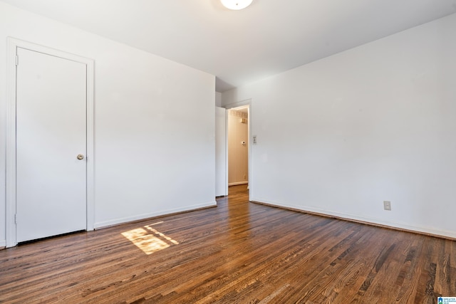 unfurnished room featuring dark wood-style floors and baseboards