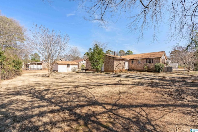 view of front of property with brick siding, fence, and central AC unit