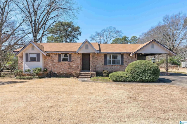 single story home featuring driveway, a front lawn, a carport, and brick siding