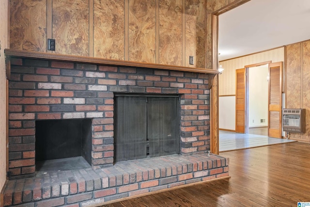 room details featuring heating unit, crown molding, a fireplace, and wood finished floors