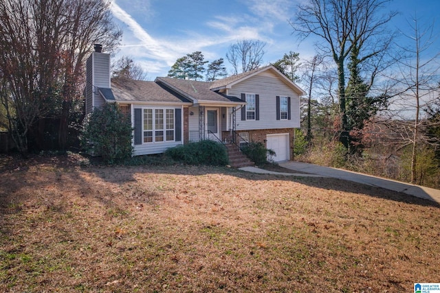 tri-level home featuring a front yard, concrete driveway, a chimney, and an attached garage