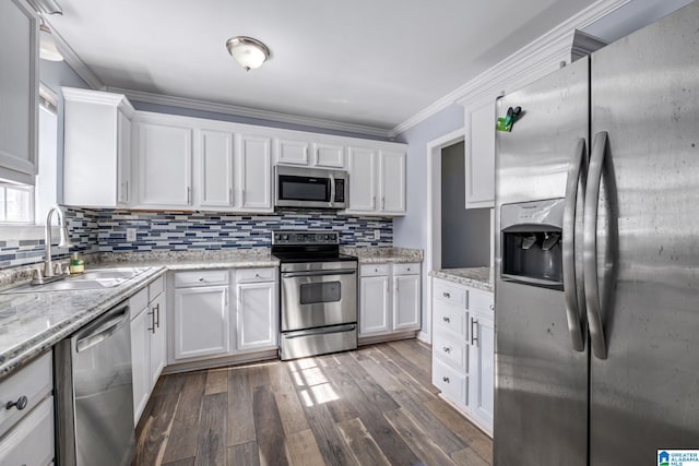 kitchen with dark wood-type flooring, a sink, white cabinetry, appliances with stainless steel finishes, and crown molding