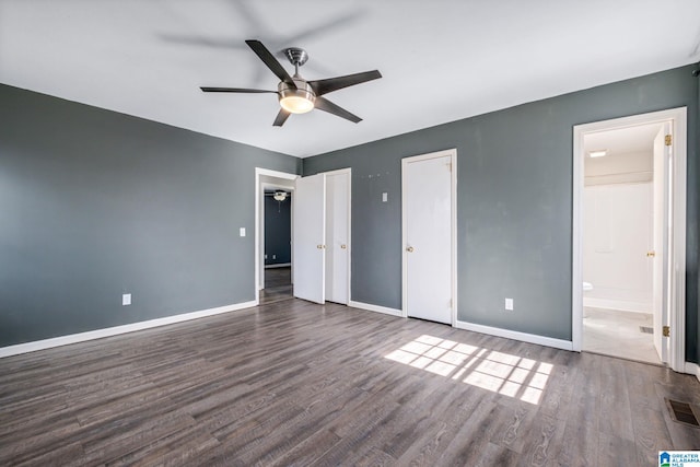 unfurnished bedroom with multiple closets, dark wood finished floors, visible vents, and baseboards