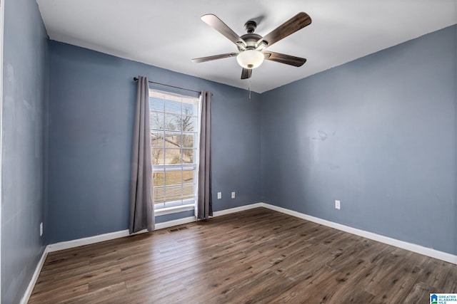 spare room with dark wood-style floors, visible vents, and baseboards