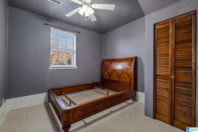 bedroom featuring light tile patterned floors, visible vents, a ceiling fan, ornamental molding, and a closet