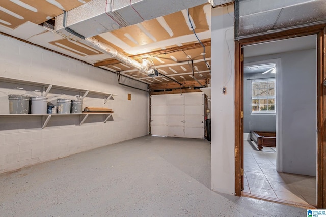 garage featuring concrete block wall and a garage door opener