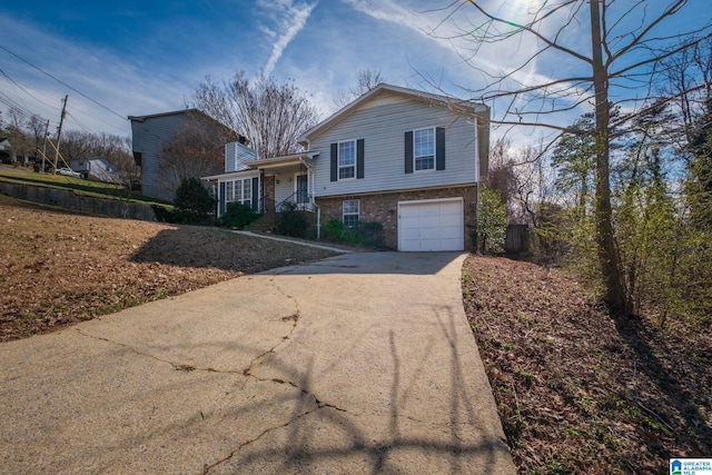 split level home with driveway, brick siding, a chimney, and an attached garage