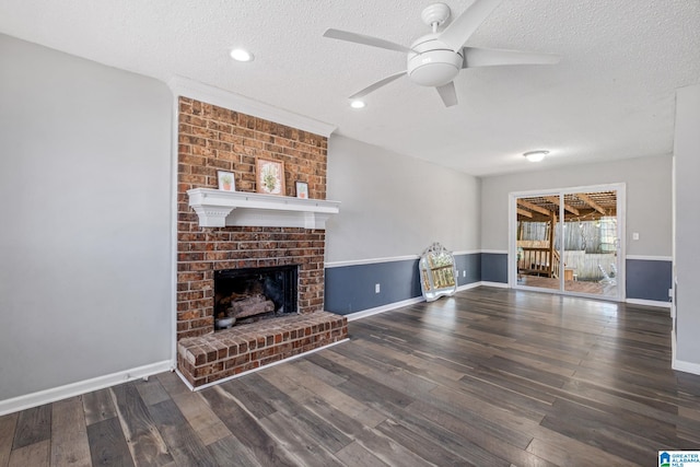 living room featuring a textured ceiling, ceiling fan, dark wood-style flooring, a fireplace, and baseboards