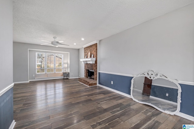 unfurnished living room featuring a textured ceiling, a fireplace, a ceiling fan, baseboards, and dark wood-style floors