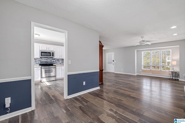 unfurnished living room featuring a textured ceiling, baseboards, dark wood finished floors, and a ceiling fan