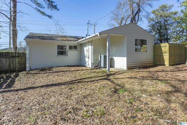 back of property with central AC unit, fence, and brick siding