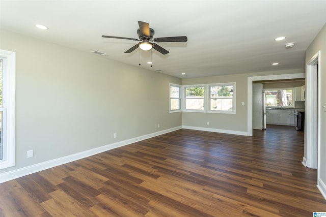 spare room with a wealth of natural light, visible vents, dark wood finished floors, and baseboards