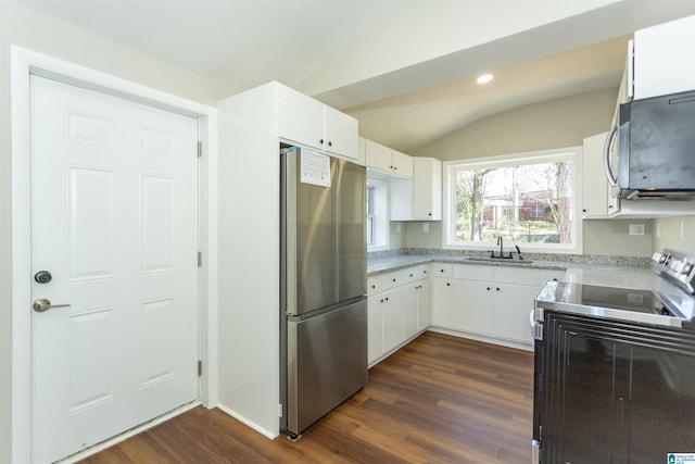 kitchen featuring vaulted ceiling, appliances with stainless steel finishes, a sink, and white cabinetry