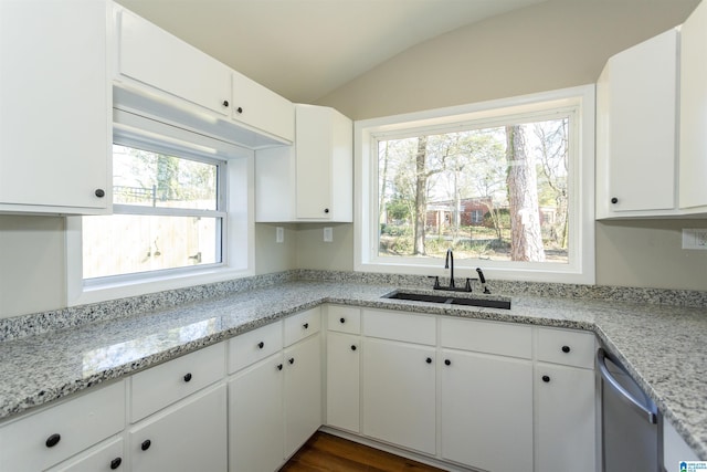 kitchen with white cabinets, lofted ceiling, light stone counters, a sink, and stainless steel dishwasher