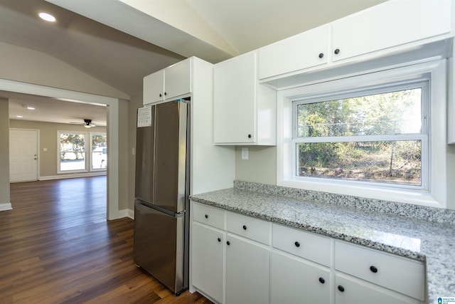 kitchen featuring light stone counters, freestanding refrigerator, white cabinets, and lofted ceiling