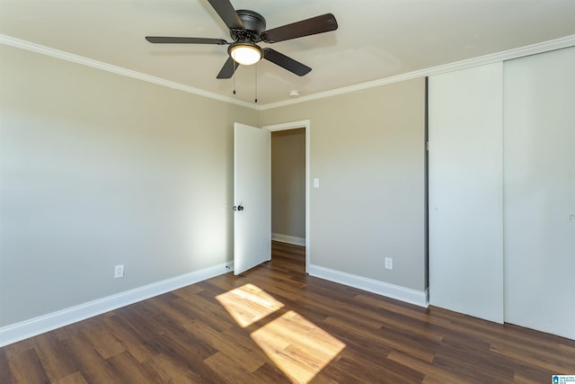 unfurnished bedroom featuring dark wood-style floors, baseboards, and crown molding