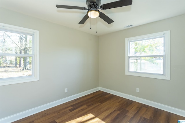 unfurnished room featuring visible vents, baseboards, dark wood-style flooring, and a wealth of natural light