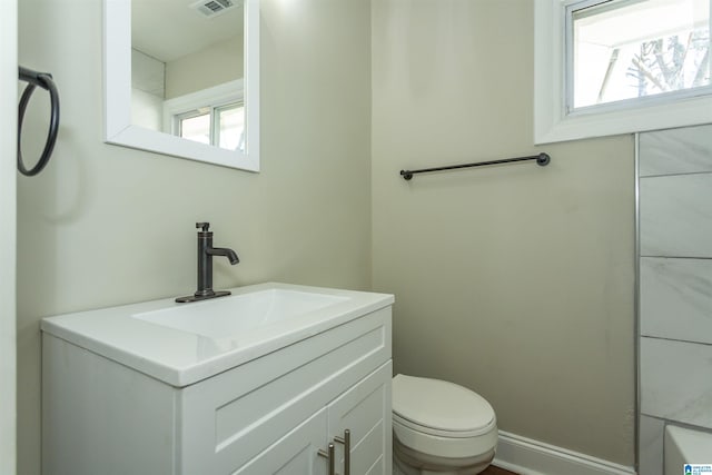 bathroom with toilet, visible vents, vanity, and a healthy amount of sunlight