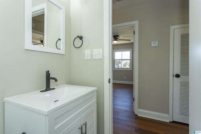 bathroom featuring ceiling fan, vanity, baseboards, and wood finished floors