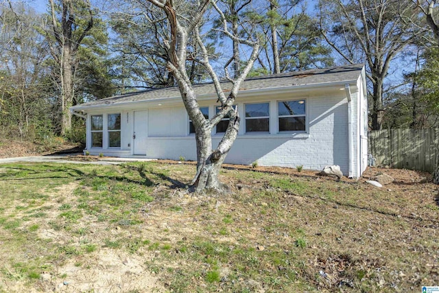 view of front of house featuring a front yard, brick siding, and fence