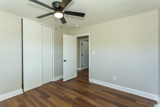 unfurnished bedroom featuring a closet, dark wood-style flooring, baseboards, and a ceiling fan