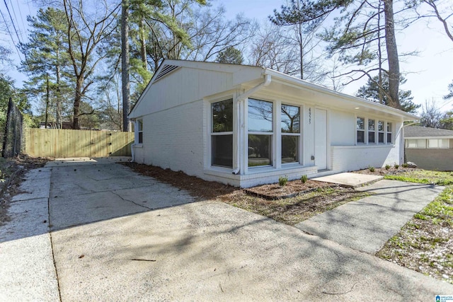 view of property exterior featuring fence and brick siding