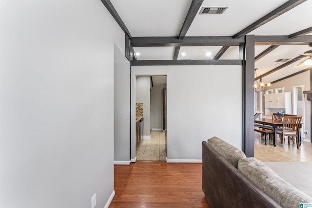 corridor featuring vaulted ceiling with beams, a notable chandelier, visible vents, baseboards, and light wood-style floors